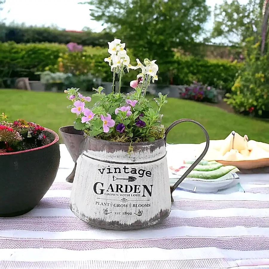 Rustic vintage jug planter filled with summer flowers including bacopa, nemesia, and calibrachoa, displayed on an outdoor garden table.